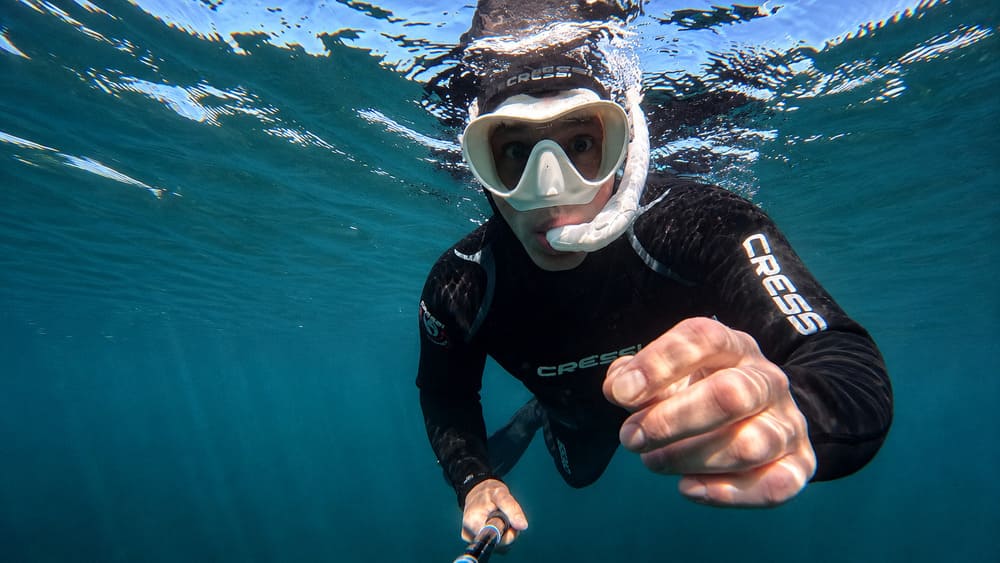 Schnorchler mit Tauchmaske und Schnorchel schwimmt direkt unter der Wasseroberfläche eines klaren Gewässers.
